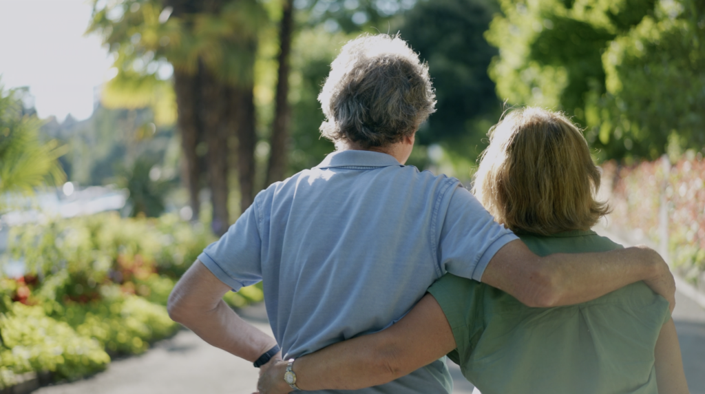 Photo from the behind of couple walking outside, arms around each other