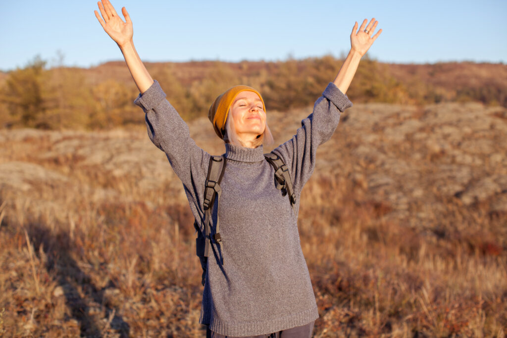 Middle aged woman hiking and going camping in nature. Person with backpack walking in autumn forest.