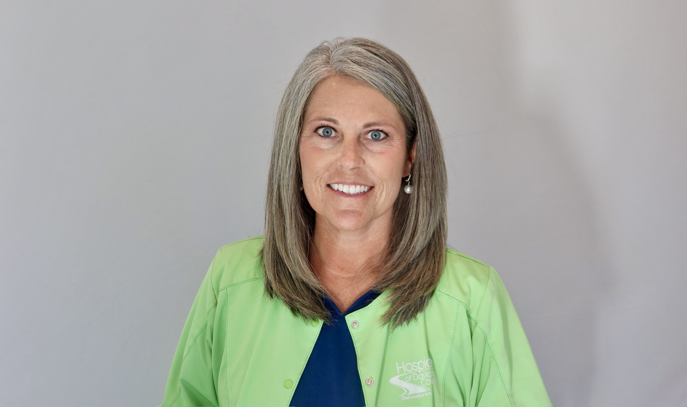 headshot of Ashley Walter who has blonde hair, wearing a green jacket and navy blue scrubs