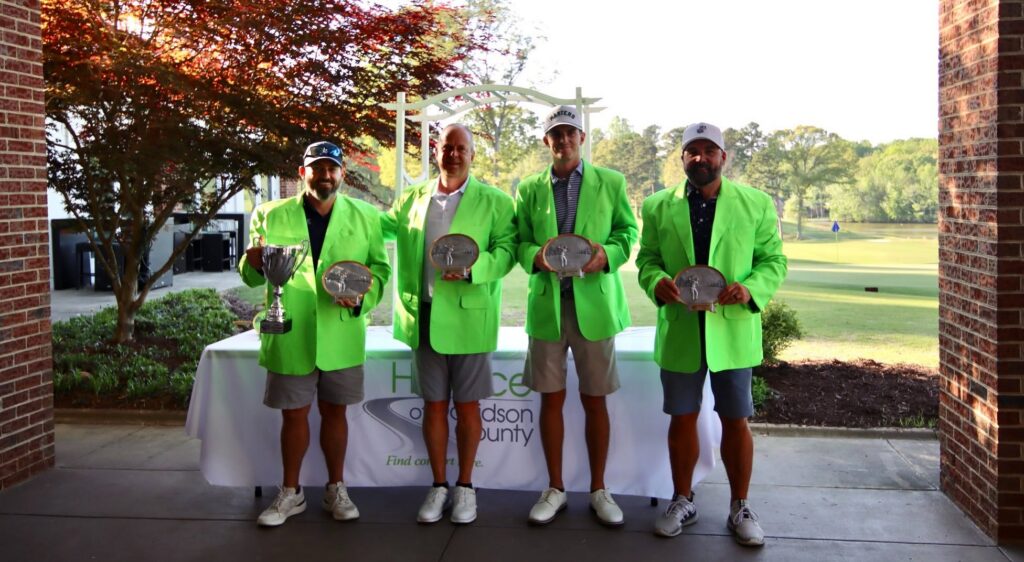 four golf tournament winners in green jackets holding trophies