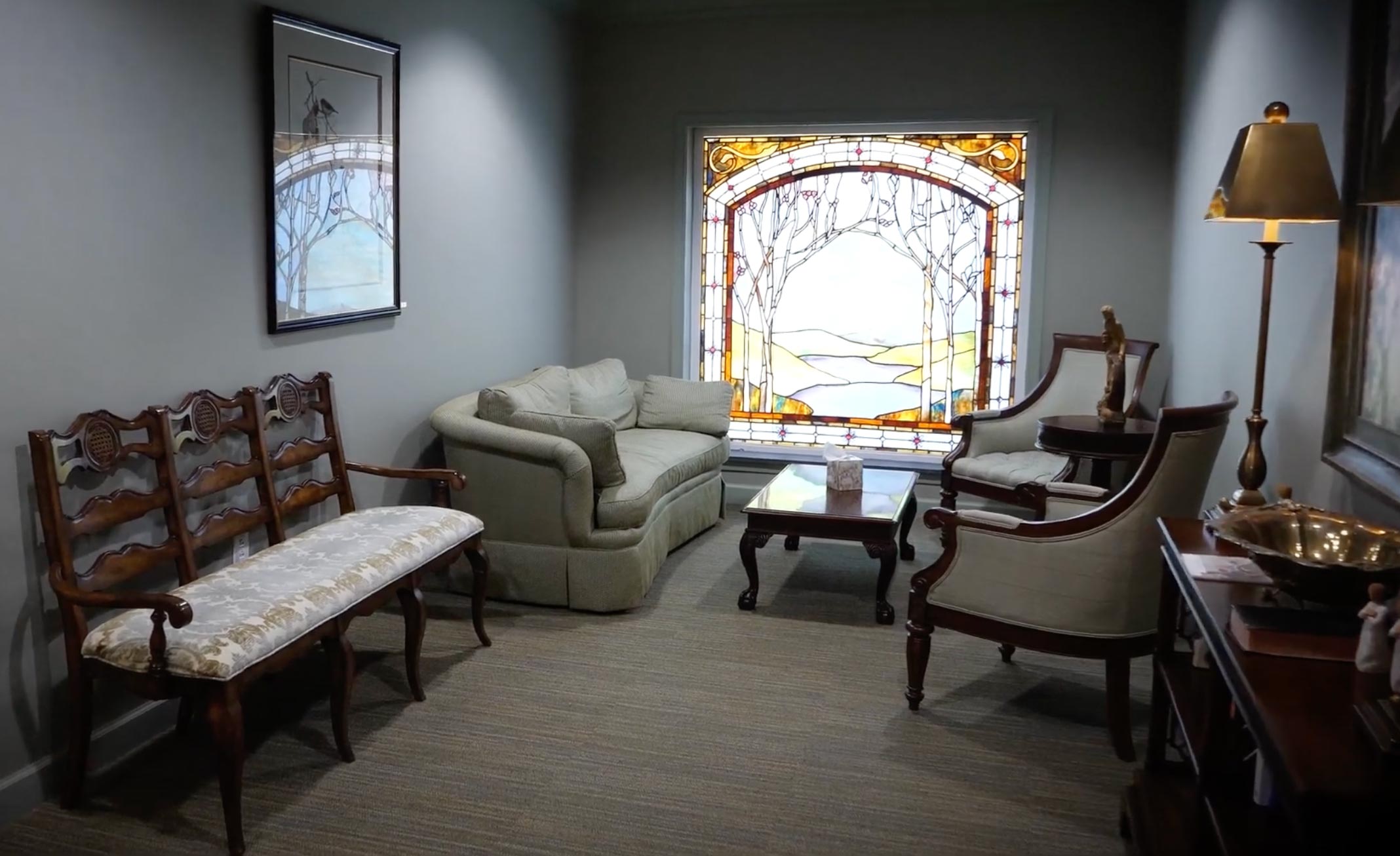 Meditation room with stained glass window, comfortable chairs, and low lighting.